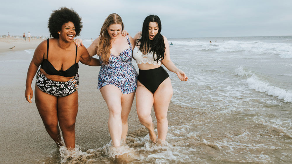 Trois jeunes femmes à la plage, pieds dans l’eau : J’aime passer du temps à la plage avec mes amis.