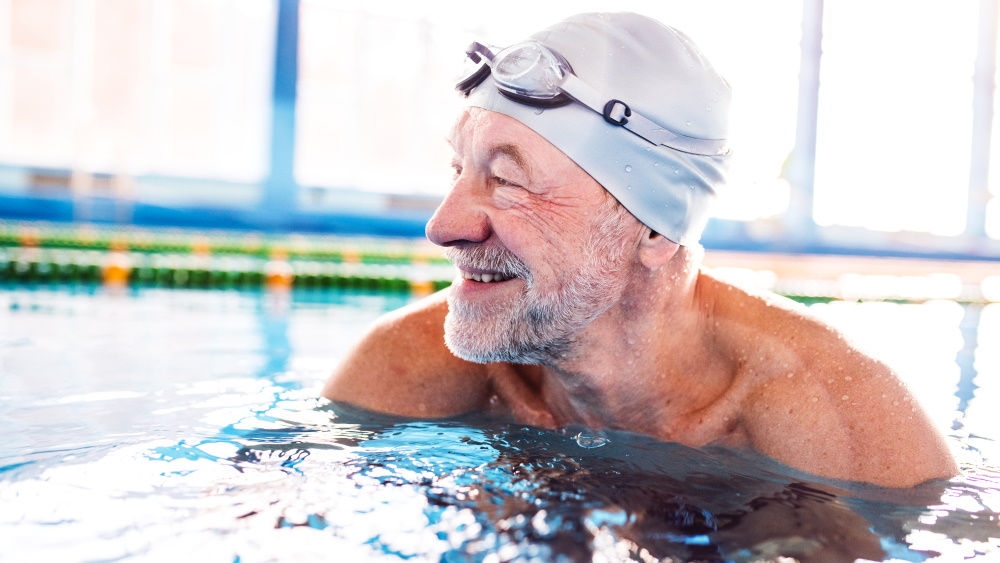 Homme âgé dans une piscine : Je suis fier de prendre cette mesure. La natation est si agréable et possible avec une stomie.