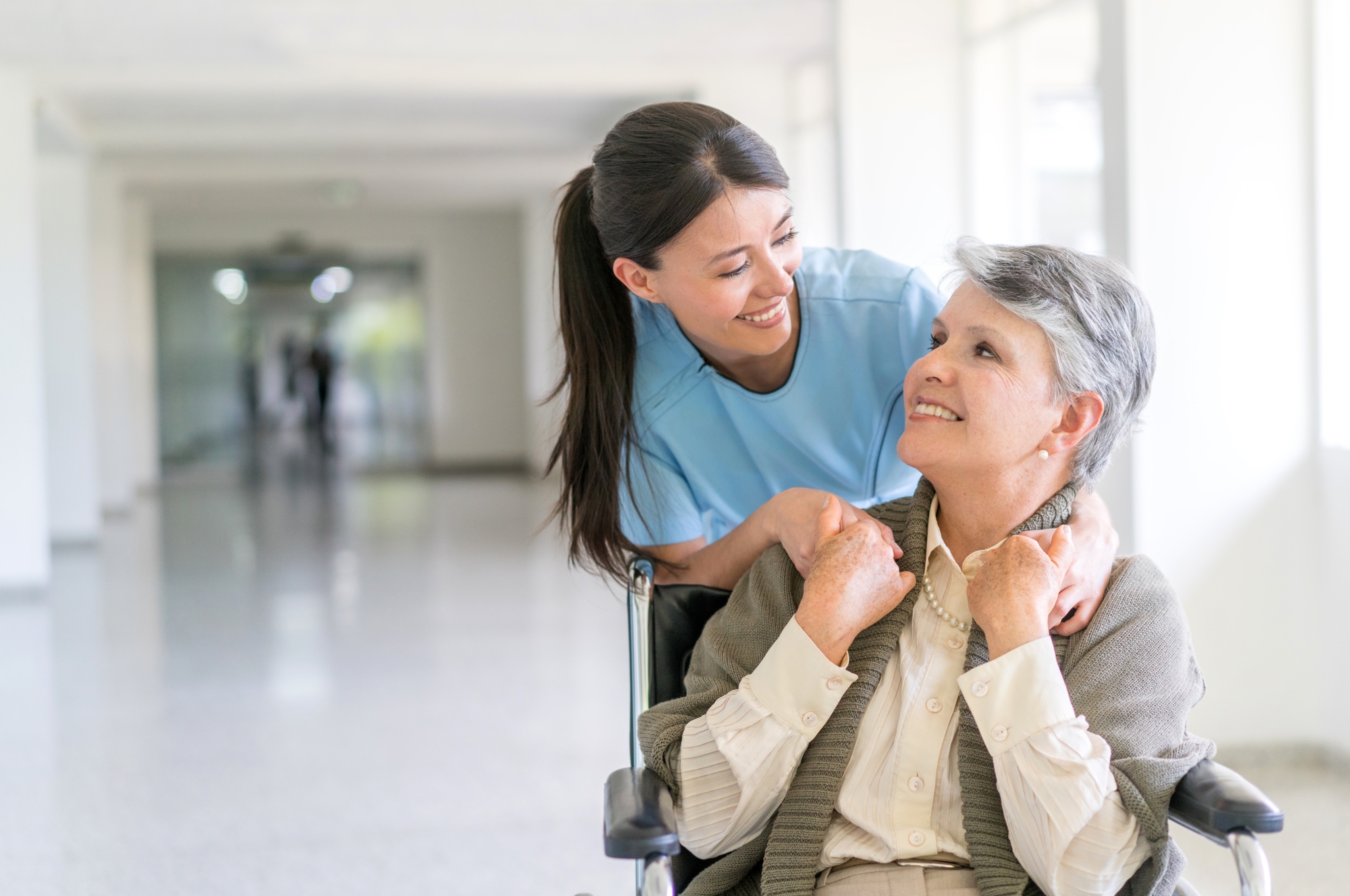 Handicap patient in a wheelchair at the hospital talking to a friendly nurse and looking very happy ??? healthcare and medicine