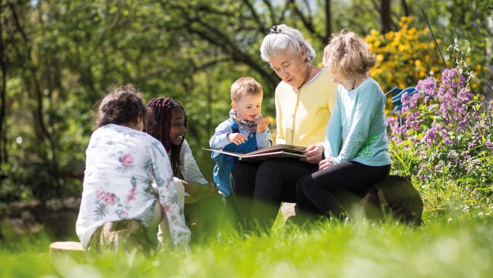 femme âgée lit dans un livre à des enfants