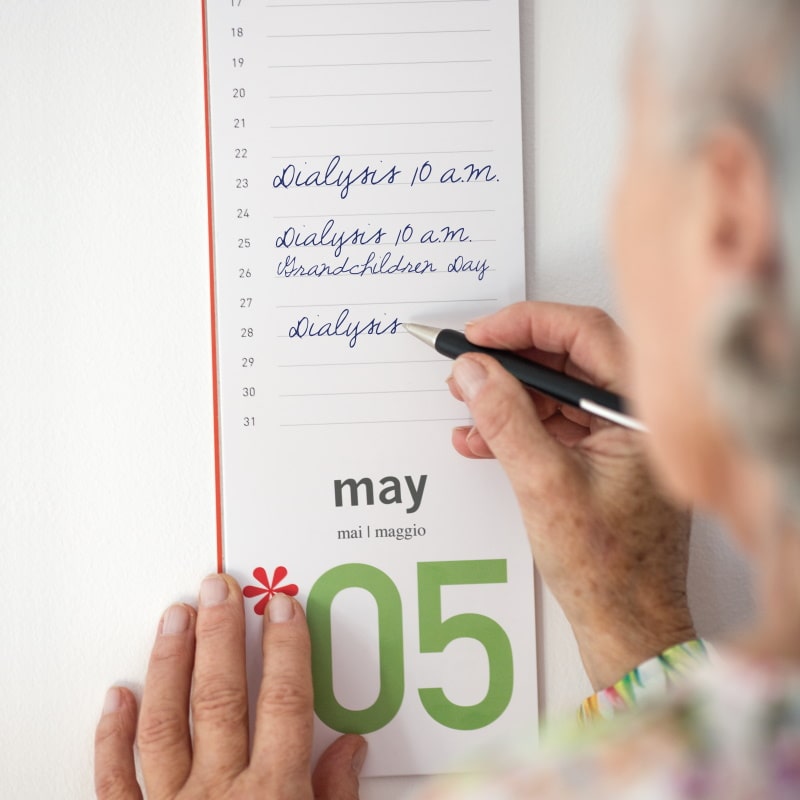 une femme âgée prend des notes dans son calendrier